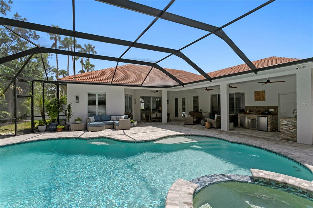 A screened-in patio features a swimming pool, a hot tub, and an outdoor kitchen area — 2801 SHORE BREEZE DRIVE, TAMPA, FL