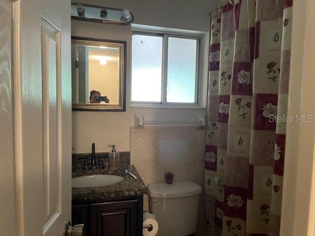 A bathroom features a dark wood vanity, granite countertop, toilet, and a floral shower curtain — 12220 CORAL REEF DRIVE, ORLANDO, FL