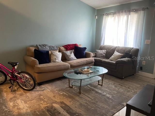 A living room features two beige sofas, a glass coffee table, and a pink bicycle — 12220 CORAL REEF DRIVE, ORLANDO, FL