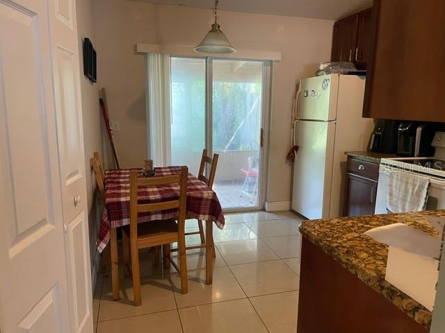 A dining area with a plaid-covered table, tile flooring, and an adjacent kitchen with appliances — 12220 CORAL REEF DRIVE, ORLANDO, FL