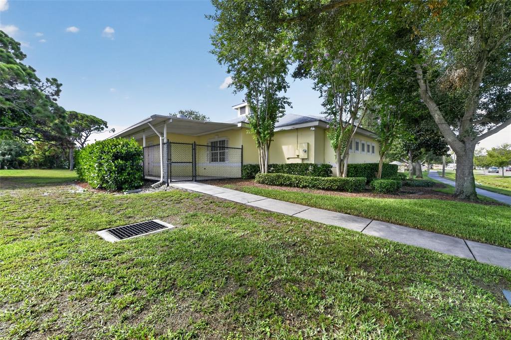 A yellow single-story building features a covered patio, chain-link fencing, and a concrete walkway — 2555 PINELLAS POINT DRIVE S, ST PETERSBURG, FL