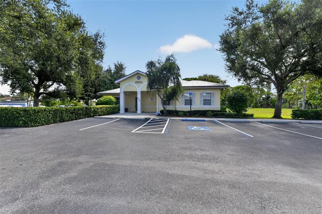 A yellow commercial building with a covered entrance sits behind a paved parking lot — 2555 PINELLAS POINT DRIVE S, ST PETERSBURG, FL