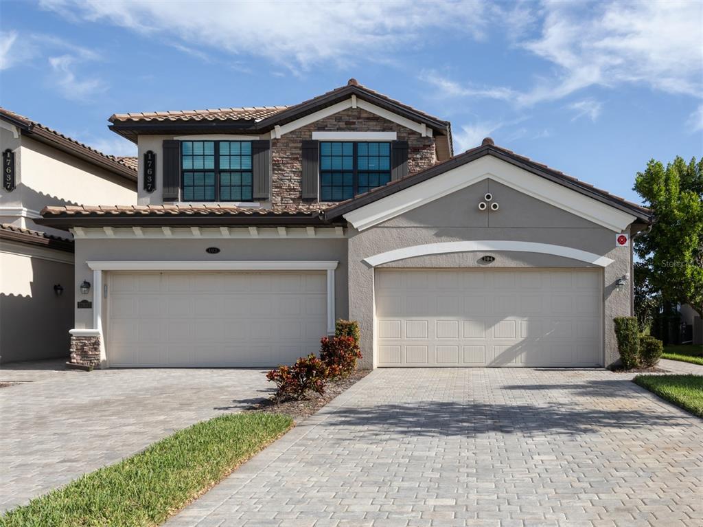 A two-story suburban house with a stone facade, tile roof, and two garage doors — 17637 GAWTHROP DRIVE UNIT 104, BRADENTON, FL