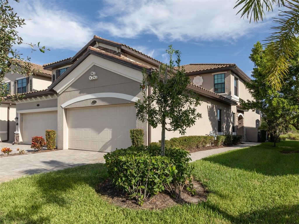 A two-story stucco townhouse with a two-car garage and a landscaped front yard — 17637 GAWTHROP DRIVE UNIT 104, BRADENTON, FL