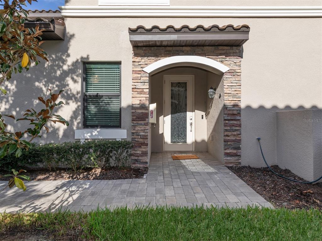 A stone-accented entryway features a glass-paneled front door, a tiled walkway, and a small window — 17637 GAWTHROP DRIVE UNIT 104, BRADENTON, FL