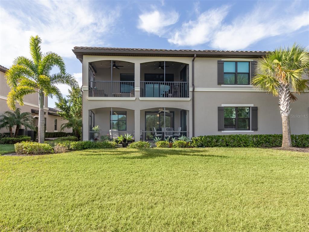 A two-story house with screened-in balconies and patios, surrounded by a lawn and palm trees — 17637 GAWTHROP DRIVE UNIT 104, BRADENTON, FL