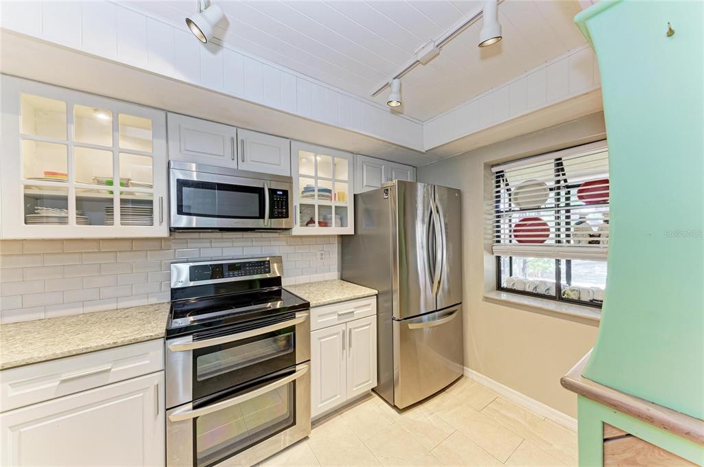A kitchen with white cabinets, stainless steel appliances, granite countertops, and a window with blinds — 4412 SPICEWOOD DRIVE UNIT E, BRADENTON, FL