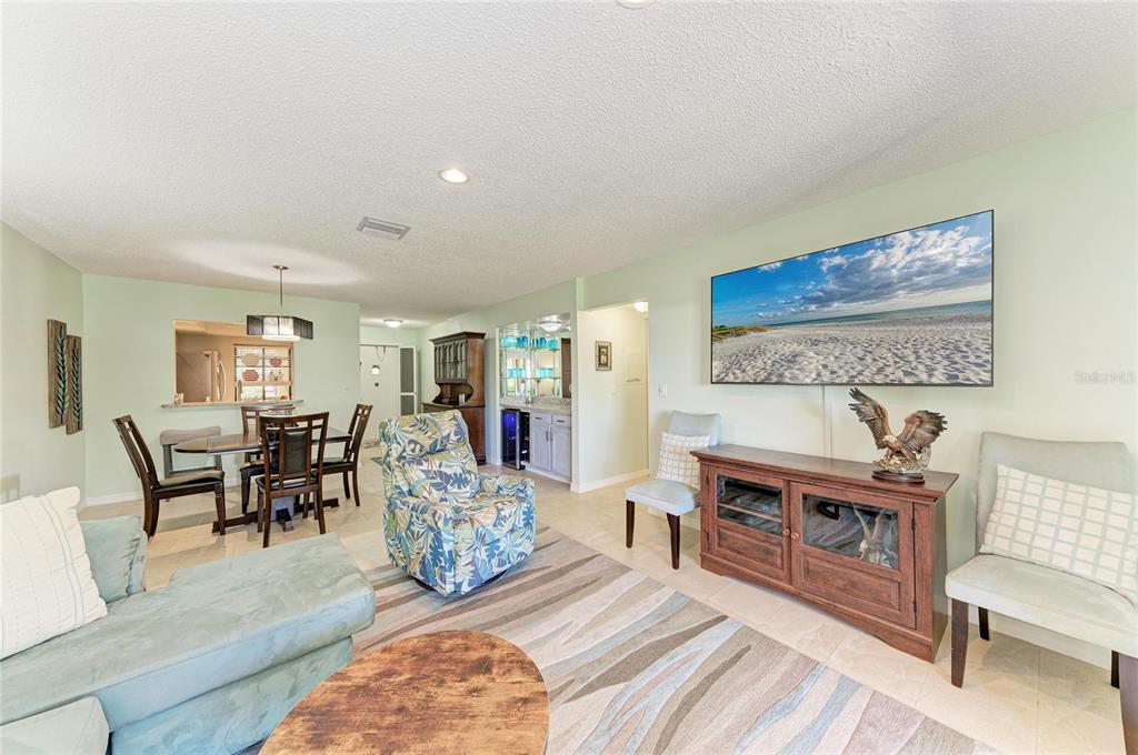 A living room features a television, a wooden media console, and a dining area — 4412 SPICEWOOD DRIVE UNIT E, BRADENTON, FL