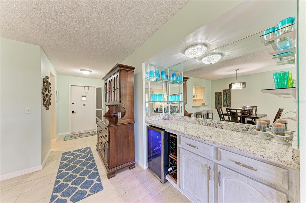A wet bar with granite countertops and a wine cooler sits beside a wooden hutch — 4412 SPICEWOOD DRIVE UNIT E, BRADENTON, FL