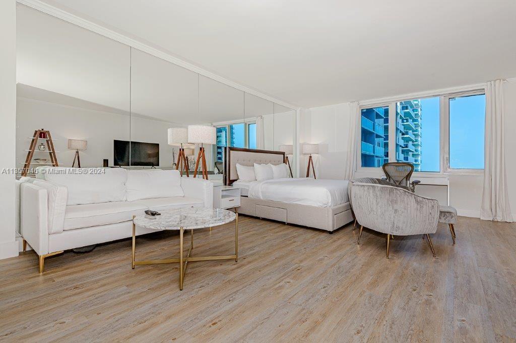 A studio apartment features a bed, sofa, marble coffee table, and a large mirrored wall — 2301 Collins Ave # 842, Miami Beach FL 33139, MIAMI BEACH, FL