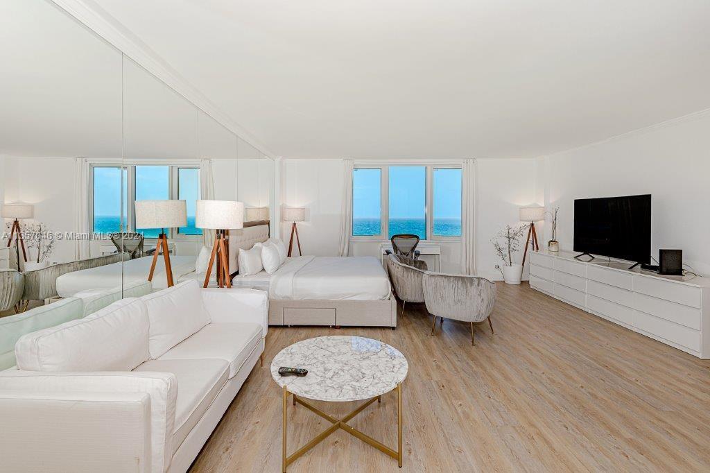 A bright bedroom features a white sofa, a bed, and floor-to-ceiling ocean view windows — 2301 Collins Ave # 842, Miami Beach FL 33139, MIAMI BEACH, FL
