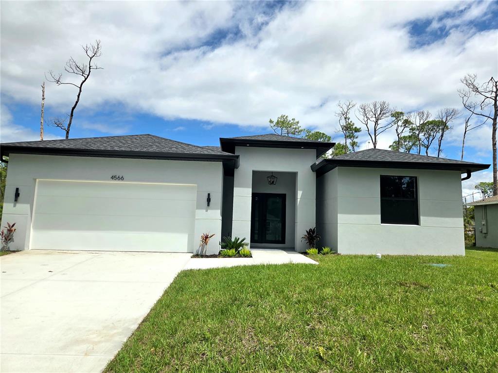 A modern, single-story house with a white stucco facade, dark roof, and a two-car garage — 3382 EVERETT TERRACE, NORTH PORT, FL