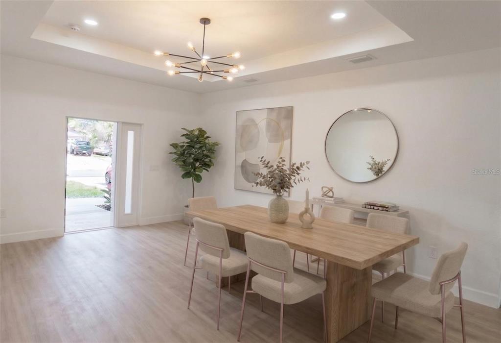 A dining room features a wooden table, light-colored chairs, a modern chandelier, and a mirror — 3382 EVERETT TERRACE, NORTH PORT, FL