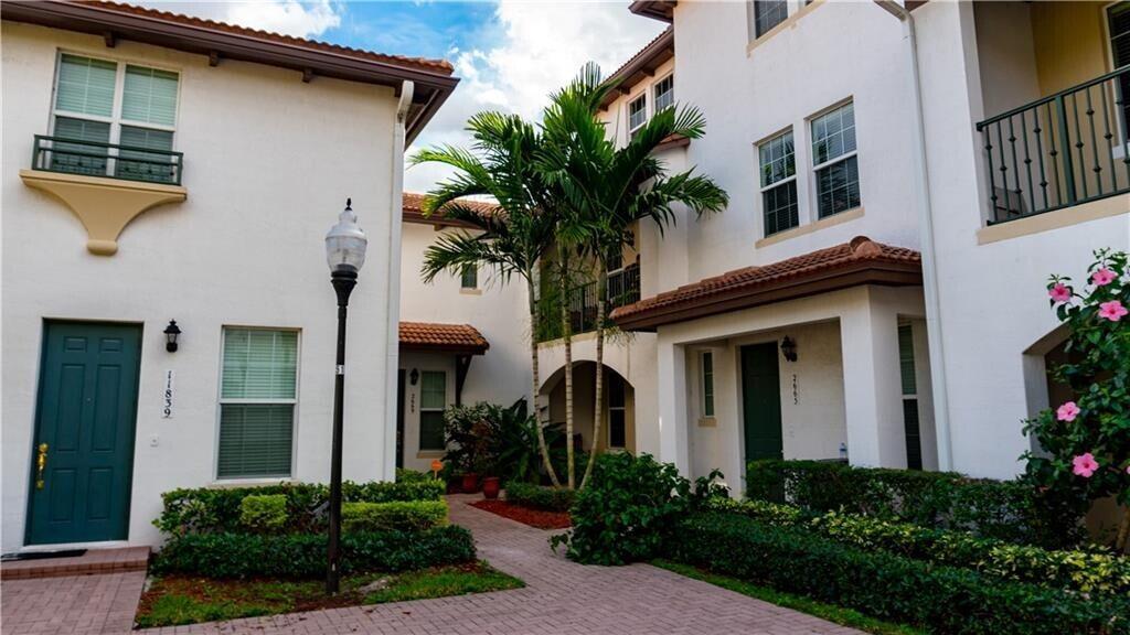 A paved walkway leads to the entrances of two white townhouses with palm trees — 2667 SW 118th Road, Miramar FL 33025, MIRAMAR, FL
