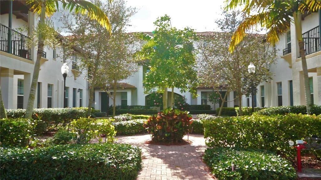 A brick walkway leads through a landscaped courtyard between two white multi-story apartment buildings — 2667 SW 118th Road, Miramar FL 33025, MIRAMAR, FL