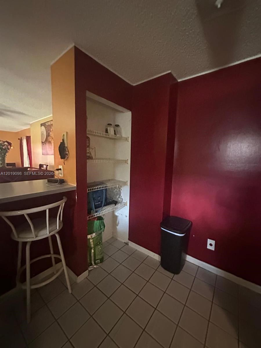 A kitchen area features a red wall, a built-in pantry with shelves, and tile flooring — 3622 NW 95th Ter # 2L, Sunrise FL 33351, SUNRISE, FL