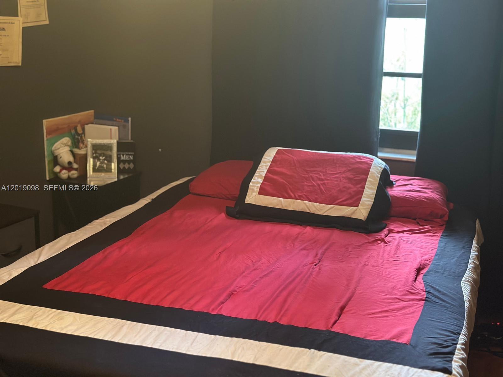 A bedroom features a bed with red, black, and white bedding against a dark wall — 3622 NW 95th Ter # 2L, Sunrise FL 33351, SUNRISE, FL