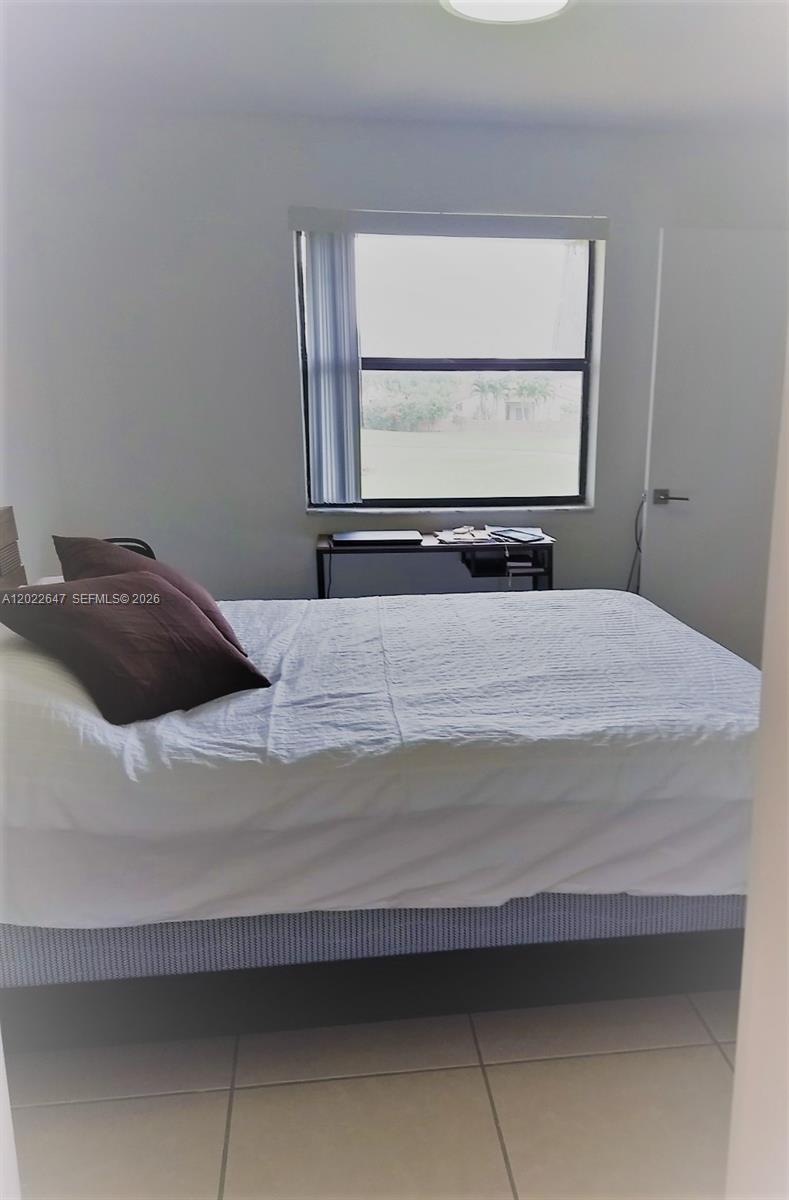 A bedroom features a bed with brown pillows, a window, and a small desk — 14857 SW 104th St # 201, Miami FL 33196, MIAMI, FL