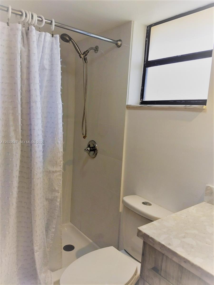 A bathroom features a walk-in shower with a handheld sprayer, a toilet, and a vanity — 14857 SW 104th St # 201, Miami FL 33196, MIAMI, FL