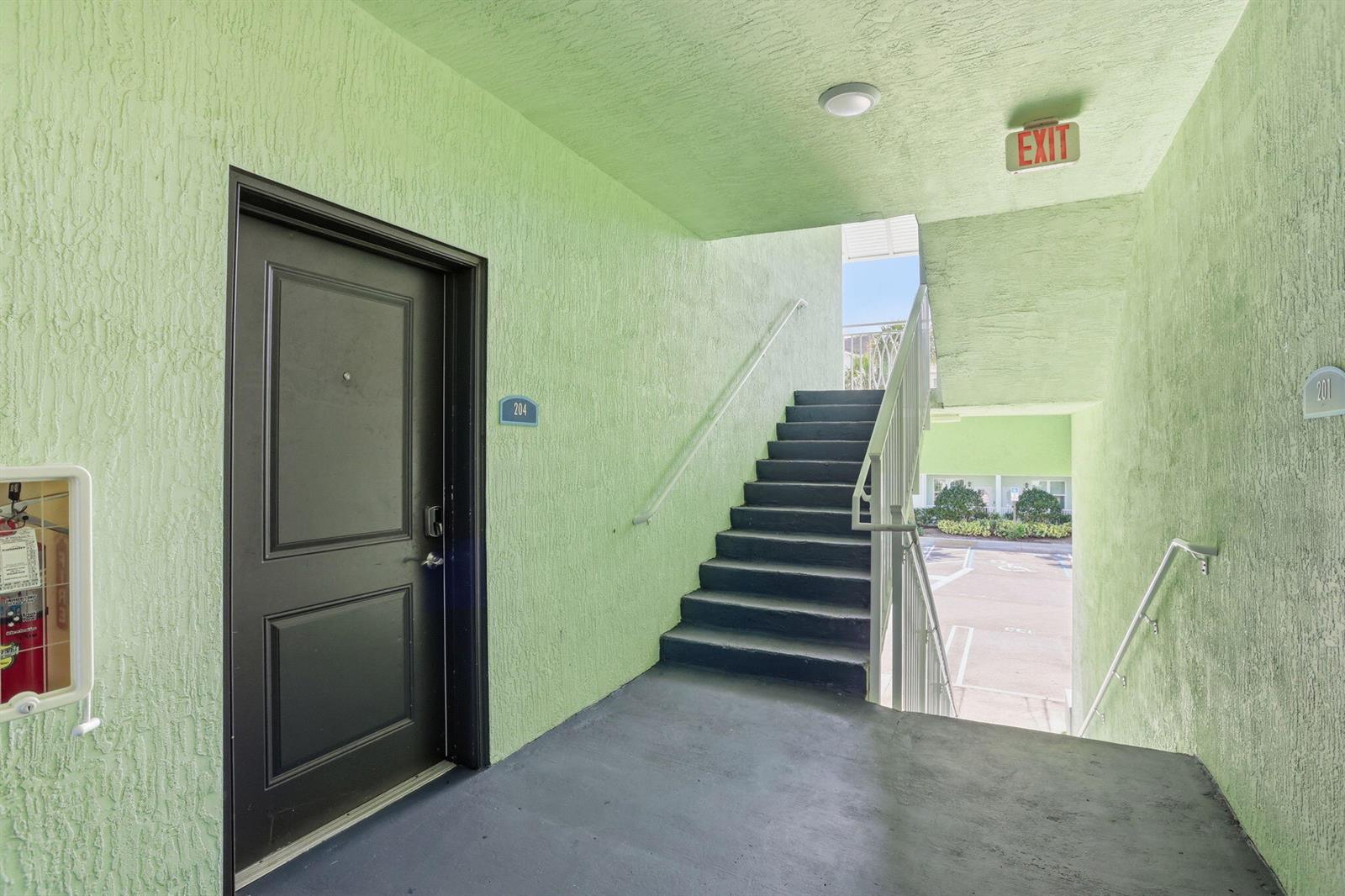 An outdoor stairwell leads to a second-floor landing with a black door and green walls — 3601 High Ridge Road # 206, Boynton Beach FL 33426, BOYNTON BEACH, FL