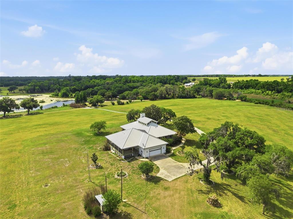 An aerial view shows a house with a metal roof situated on a large grassy lot — 18610 TOWNSEND HOUSE ROAD, DADE CITY, FL