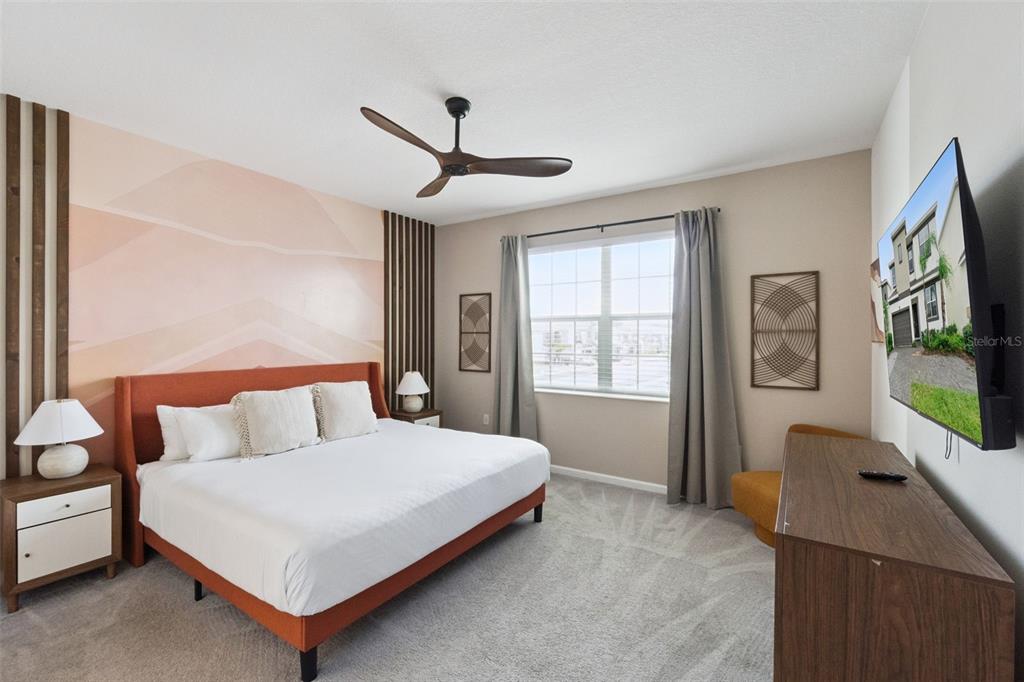 A bedroom features a king bed with an orange frame, a mural, and a television — 262 MARCELLO BOULEVARD, KISSIMMEE, FL