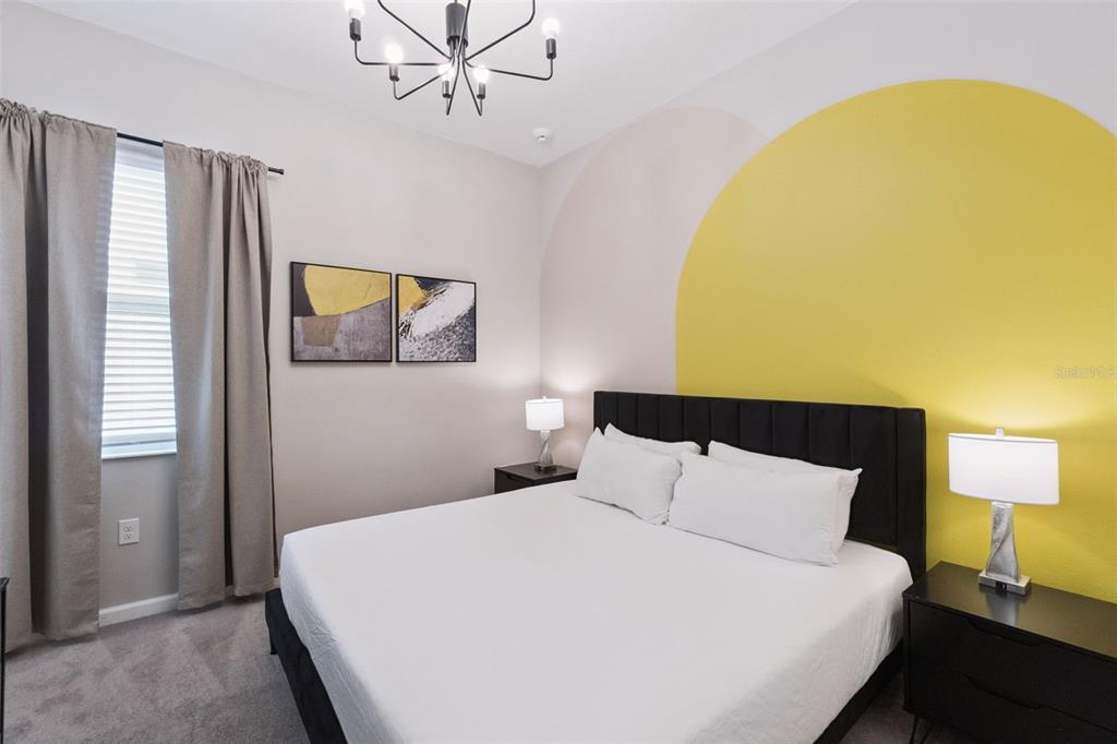 A bedroom features a black bed frame, a yellow painted arch, and two bedside lamps — 262 MARCELLO BOULEVARD, KISSIMMEE, FL
