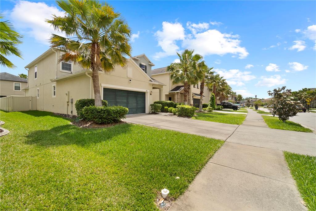 A two-story suburban house with a tan exterior, a two-car garage, and palm trees — 1588 LUDINGTON AVENUE, WESLEY CHAPEL, FL