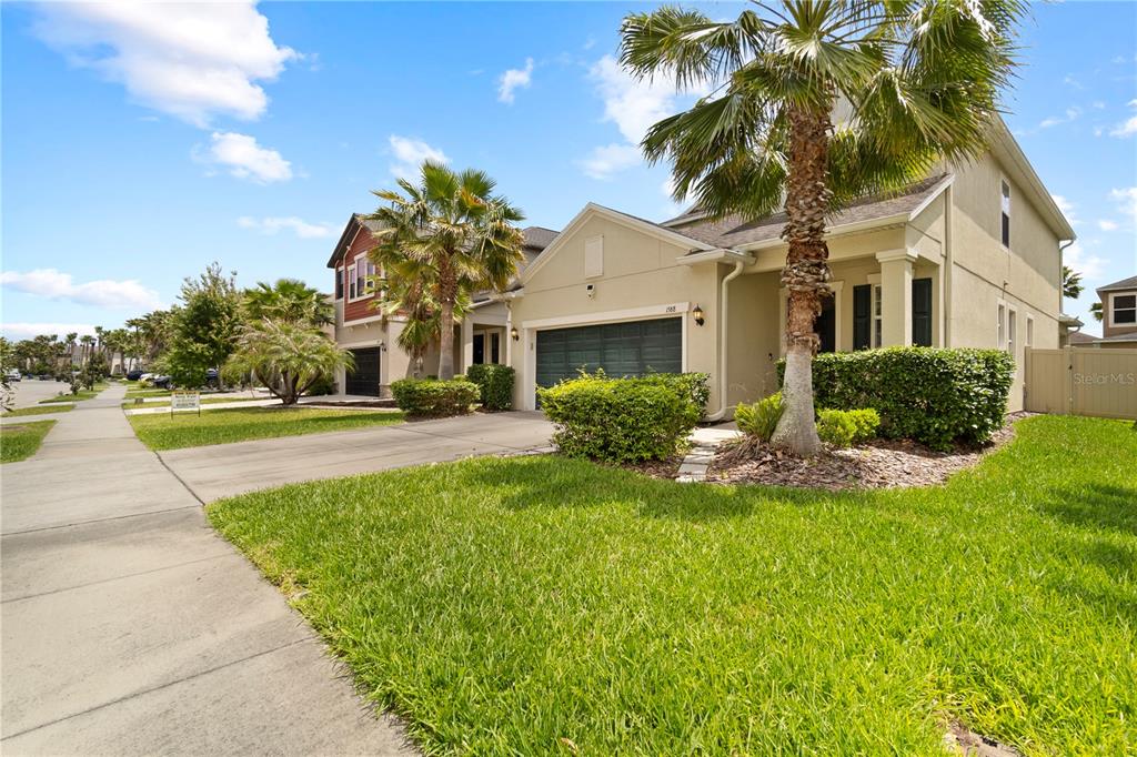A two-story suburban house with a tan exterior, a two-car garage, and a palm tree — 1588 LUDINGTON AVENUE, WESLEY CHAPEL, FL