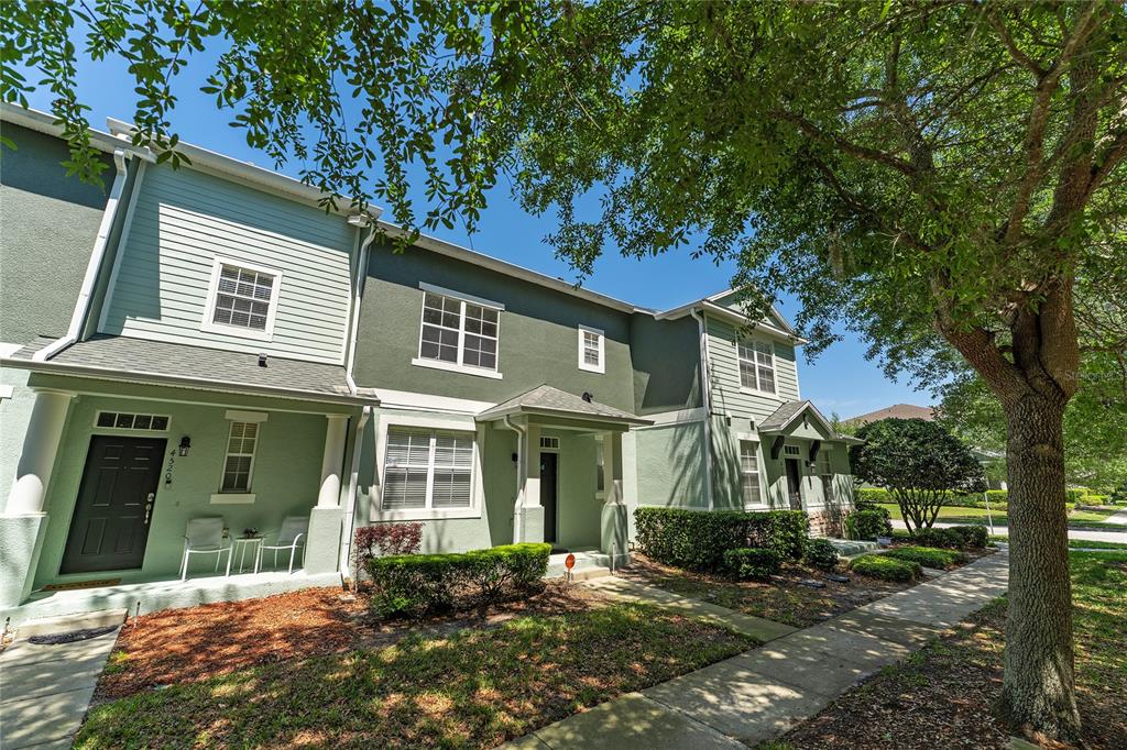 A row of two-story townhomes with light green siding and dark green stucco exteriors — 4510 CAPITAL BOULEVARD, ST CLOUD, FL