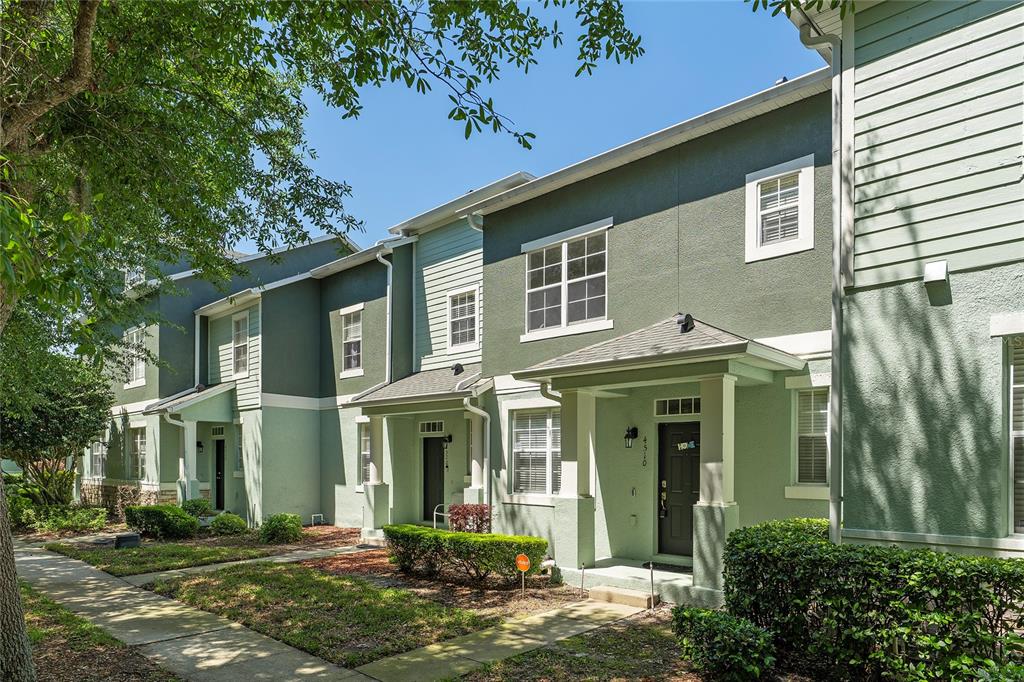 A row of multi-story townhomes with green stucco and siding exteriors under a clear sky — 4510 CAPITAL BOULEVARD, ST CLOUD, FL