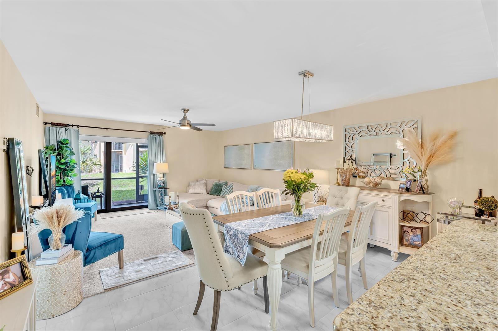 A dining area with a wooden table and chairs sits adjacent to a living room — 912 SW 9th Street Circle # 105, Boca Raton FL 33486, BOCA RATON, FL
