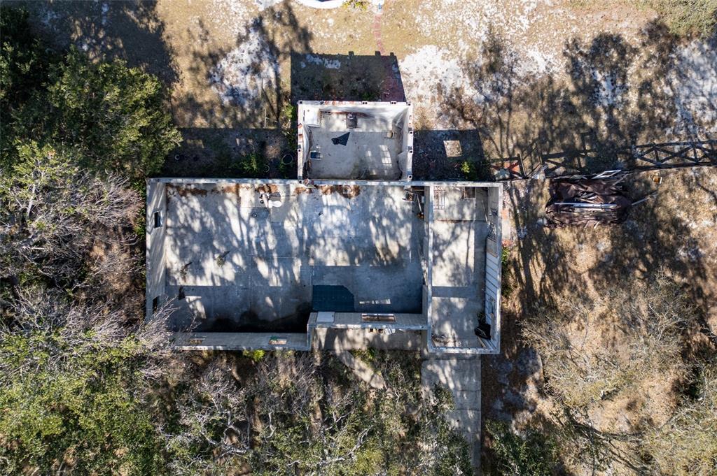 Aerial view of a roofless, dilapidated structure with concrete walls and a shipping container attachment — 8725 TREASURE ISLAND ROAD, LEESBURG, FL