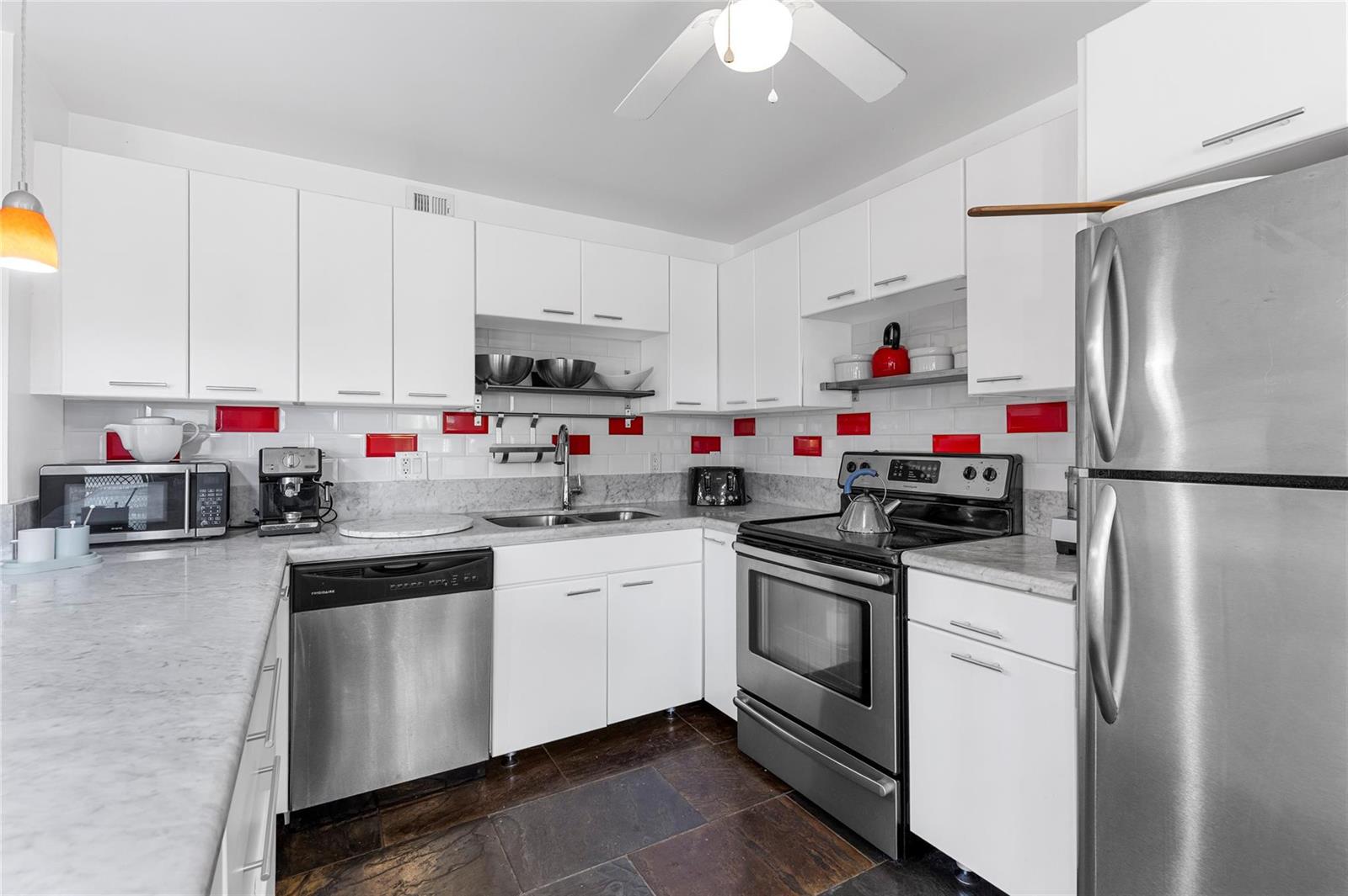 A kitchen with white cabinets, stainless steel appliances, marble countertops, and red tiled accents — 4044 Ventnor O # 4044, Deerfield Beach FL 33442, DEERFIELD BEACH, FL