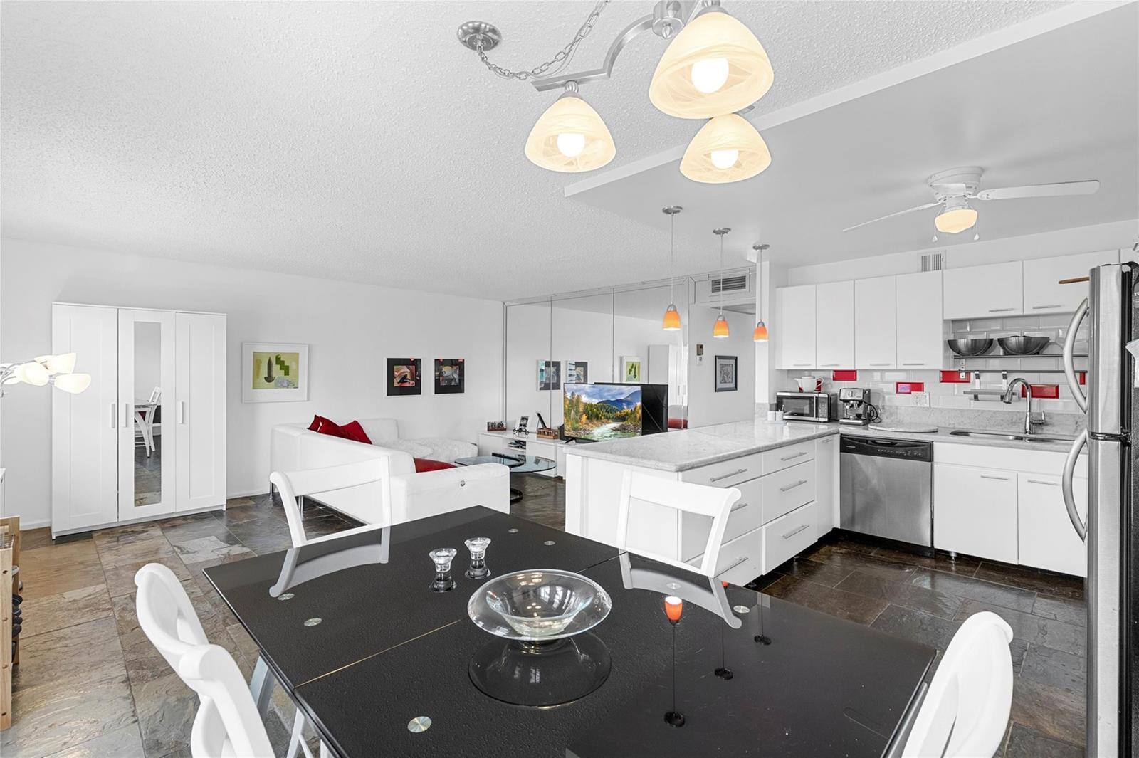 An open-concept kitchen and living area features white cabinetry, a black dining table, and tile flooring — 4044 Ventnor O # 4044, Deerfield Beach FL 33442, DEERFIELD BEACH, FL