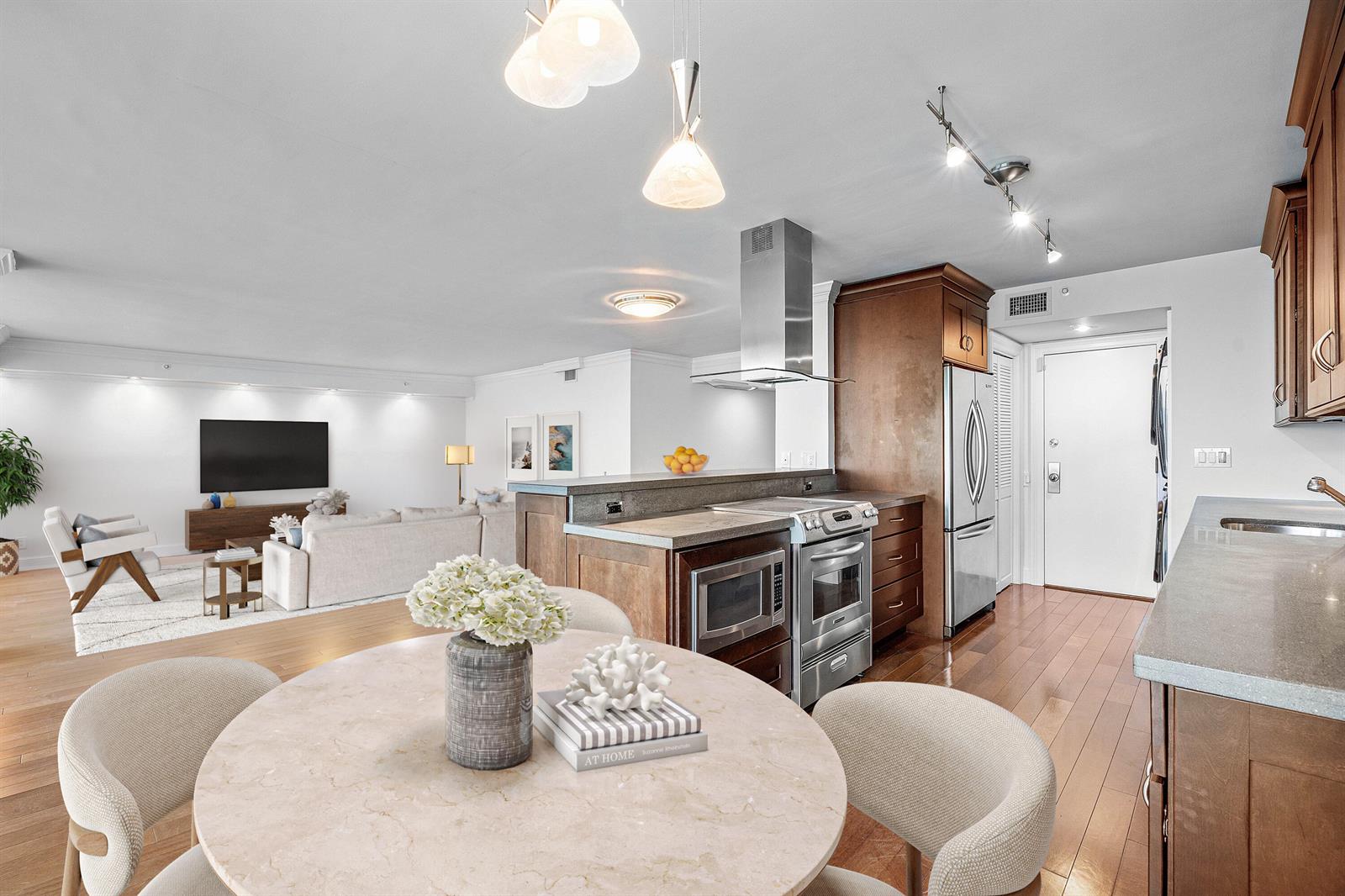 A kitchen with wood cabinets and stainless steel appliances overlooks a living area with hardwood floors — 250 S Ocean Boulevard # 11c, Boca Raton FL 33432, BOCA RATON, FL