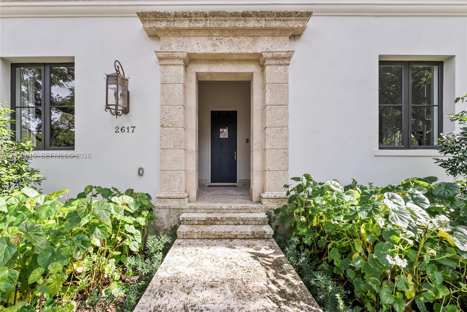 A stone-framed entryway with a dark door leads to a house with white walls — 2617 Anderson Rd, Coral Gables FL 33134, CORAL GABLES, FL