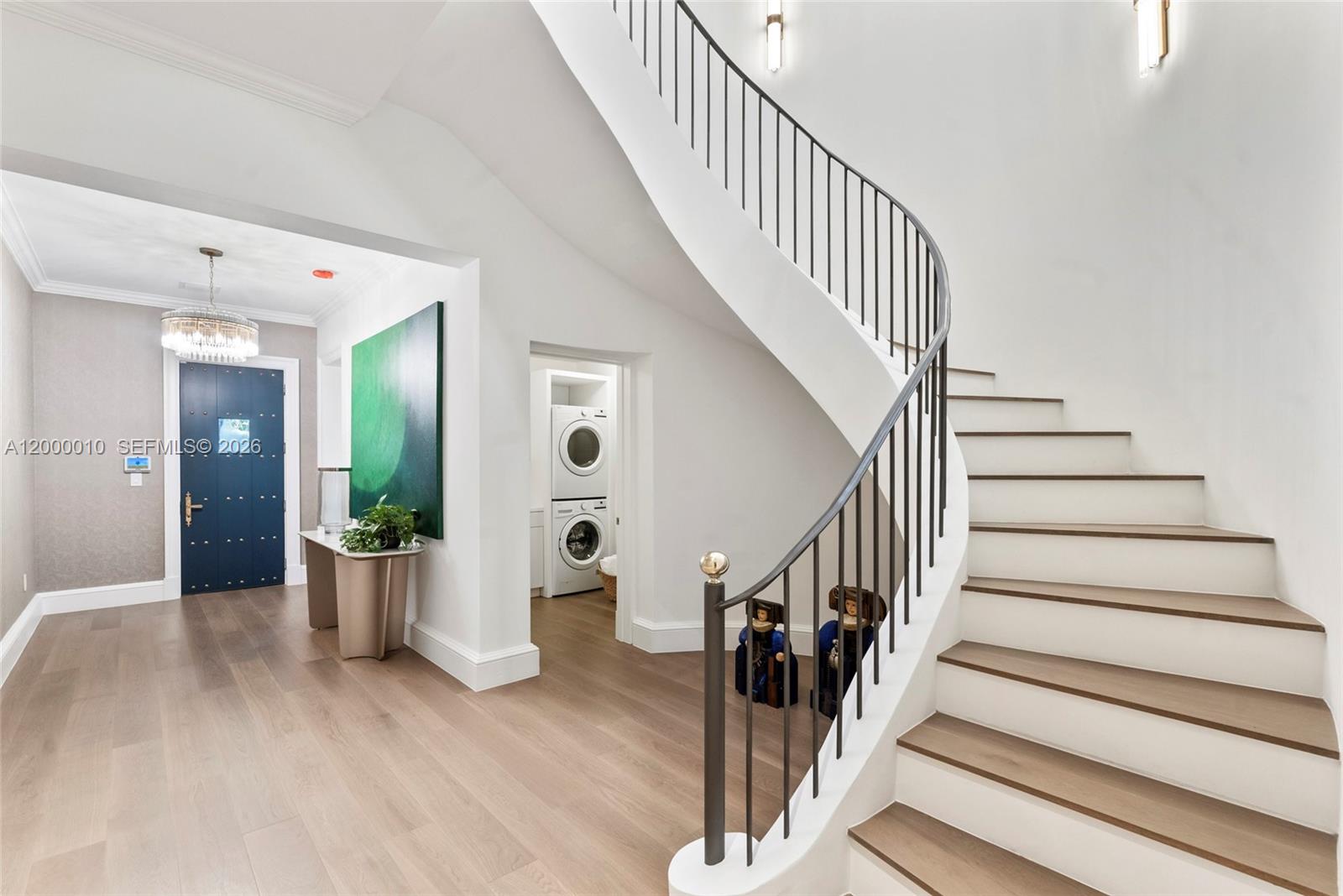 A curved staircase with a metal railing stands in a bright foyer with hardwood floors — 2617 Anderson Rd, Coral Gables FL 33134, CORAL GABLES, FL