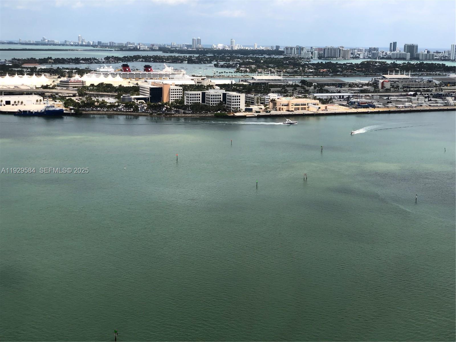 An aerial view shows a harbor with cruise ships, buildings, and boats on the water — 900 Brickell Key Blvd # 1602, Miami FL 33131, MIAMI, FL
