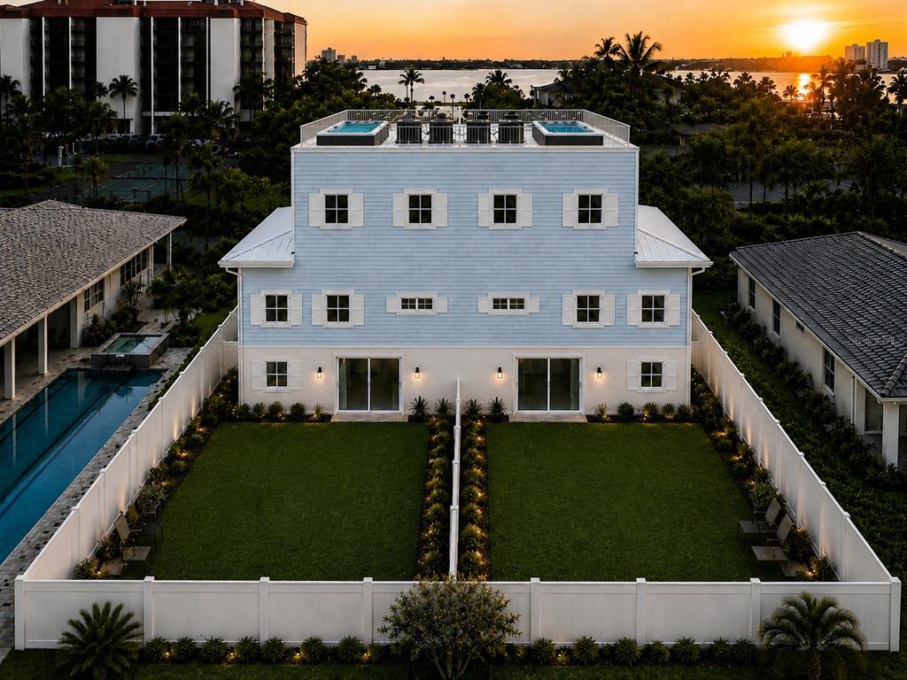 An aerial view of a light blue duplex with two rooftop pools and fenced backyards — 7045 HIBISCUS, SOUTH PASADENA, FL