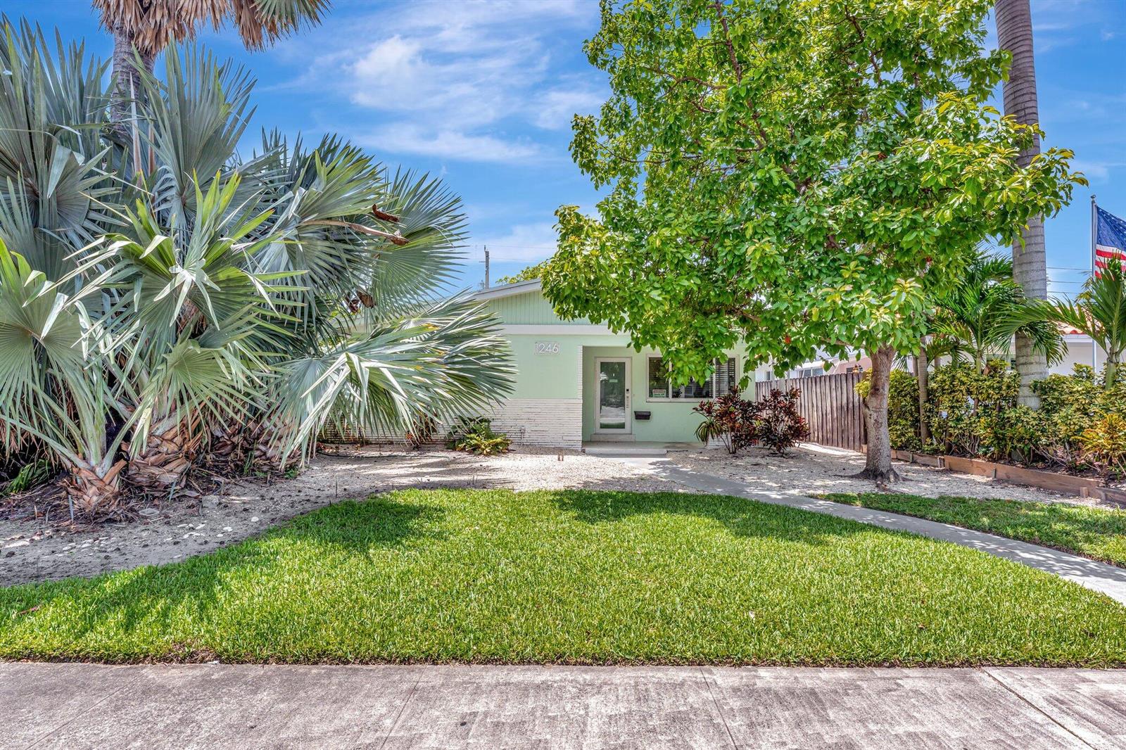 A single-story house with a green exterior, a front lawn, and lush tropical landscaping — 1246 Johnson Street, Hollywood FL 33019, HOLLYWOOD, FL