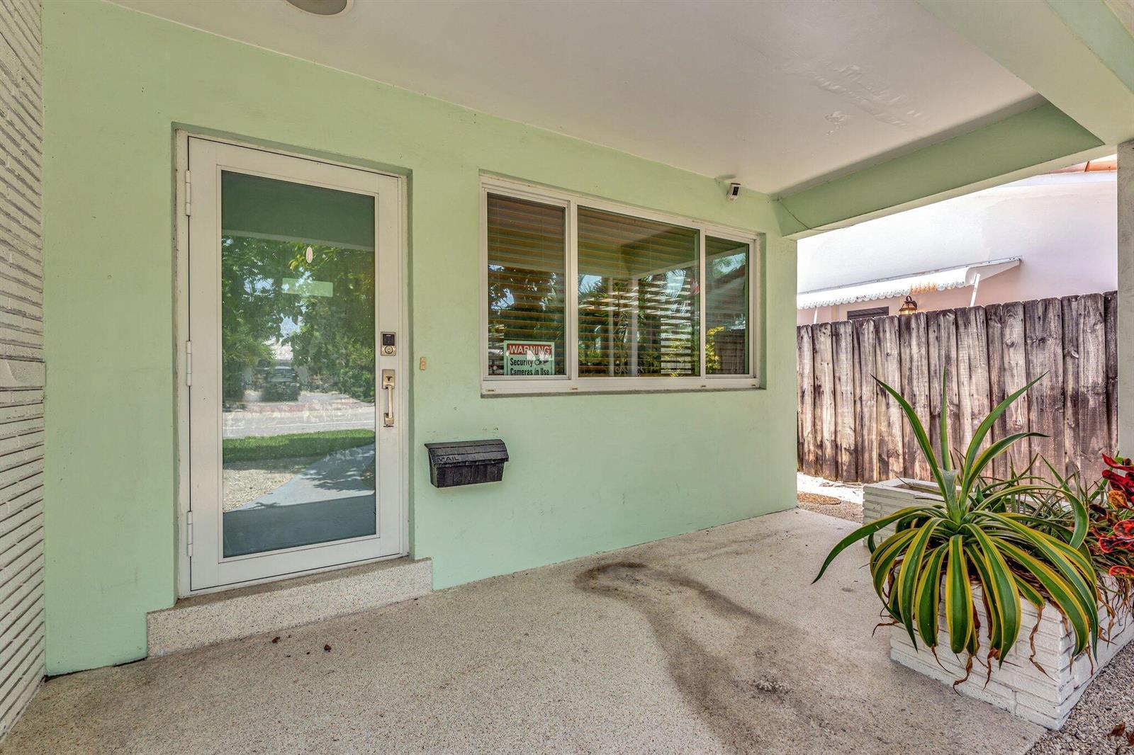 A light green exterior wall features a glass-paneled door, a window, and a mailbox — 1246 Johnson Street, Hollywood FL 33019, HOLLYWOOD, FL