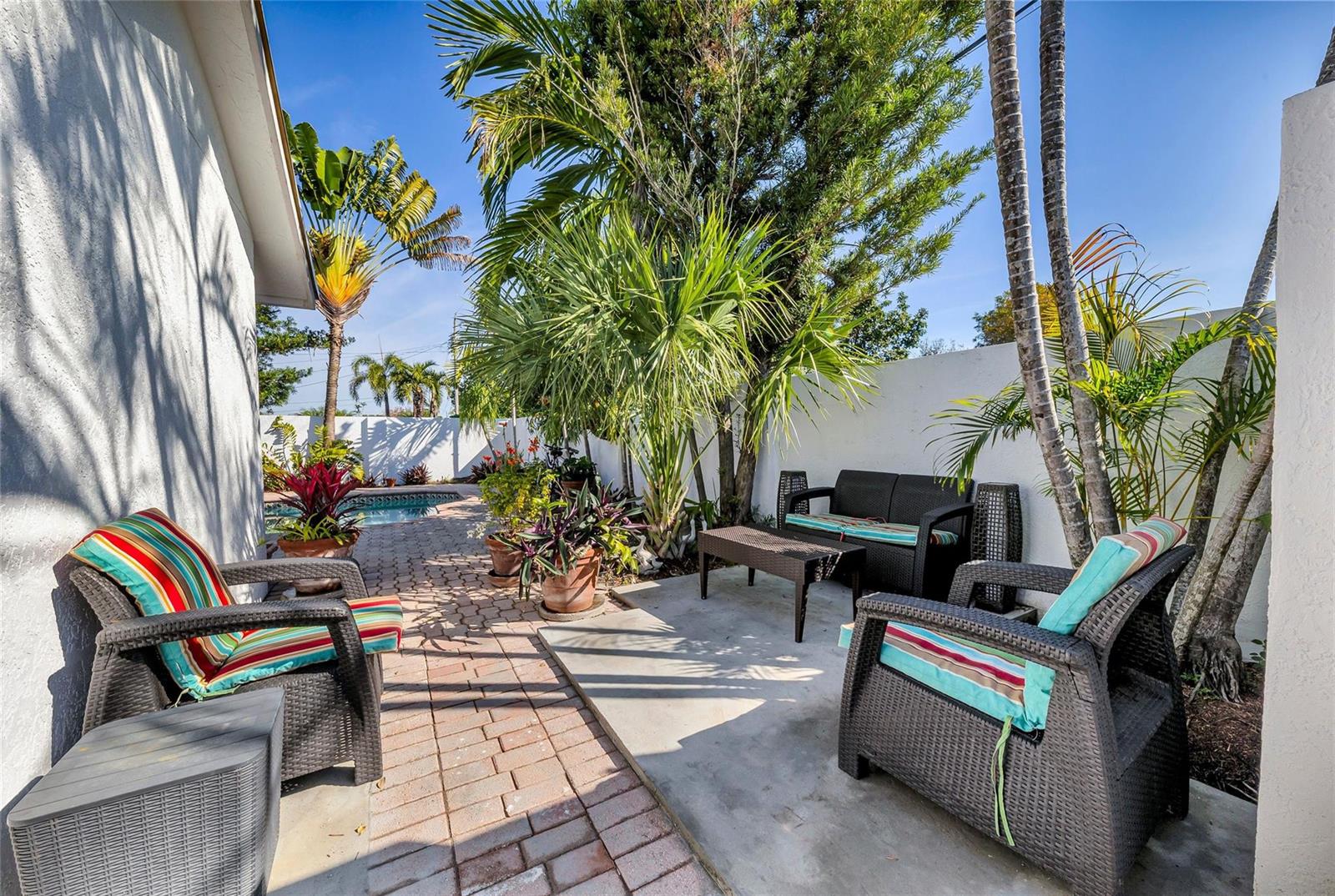 A patio area features wicker furniture, potted plants, and a brick walkway beside a pool — 307 N Highland Drive, Hollywood FL 33021, HOLLYWOOD, FL