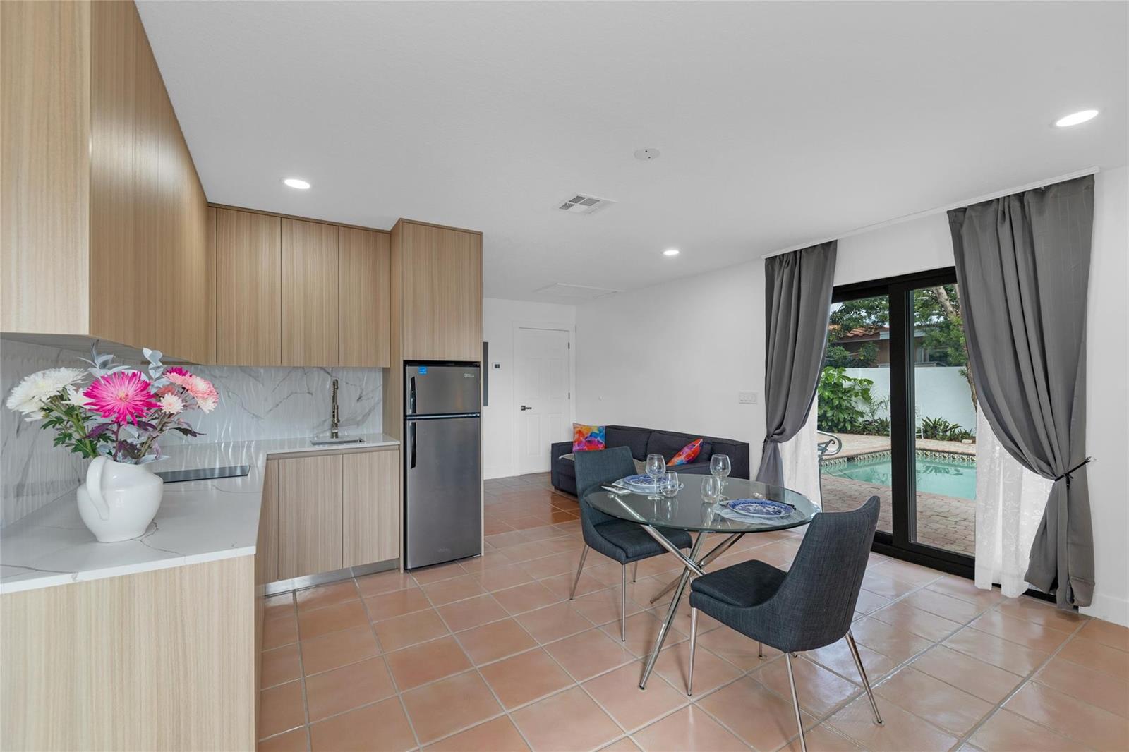 A kitchen and dining area with light wood cabinets, tile floors, and a sliding glass door — 307 N Highland Drive, Hollywood FL 33021, HOLLYWOOD, FL