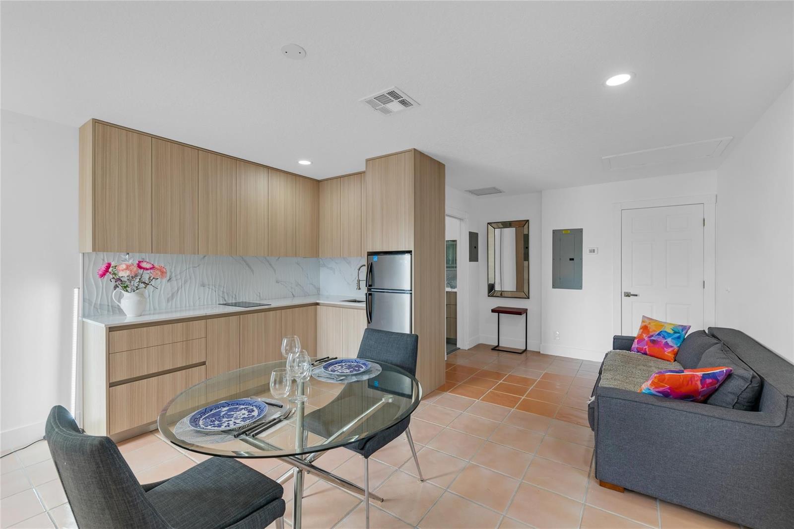 A kitchen and living area with light wood cabinets, a glass table, and tile floors — 307 N Highland Drive, Hollywood FL 33021, HOLLYWOOD, FL