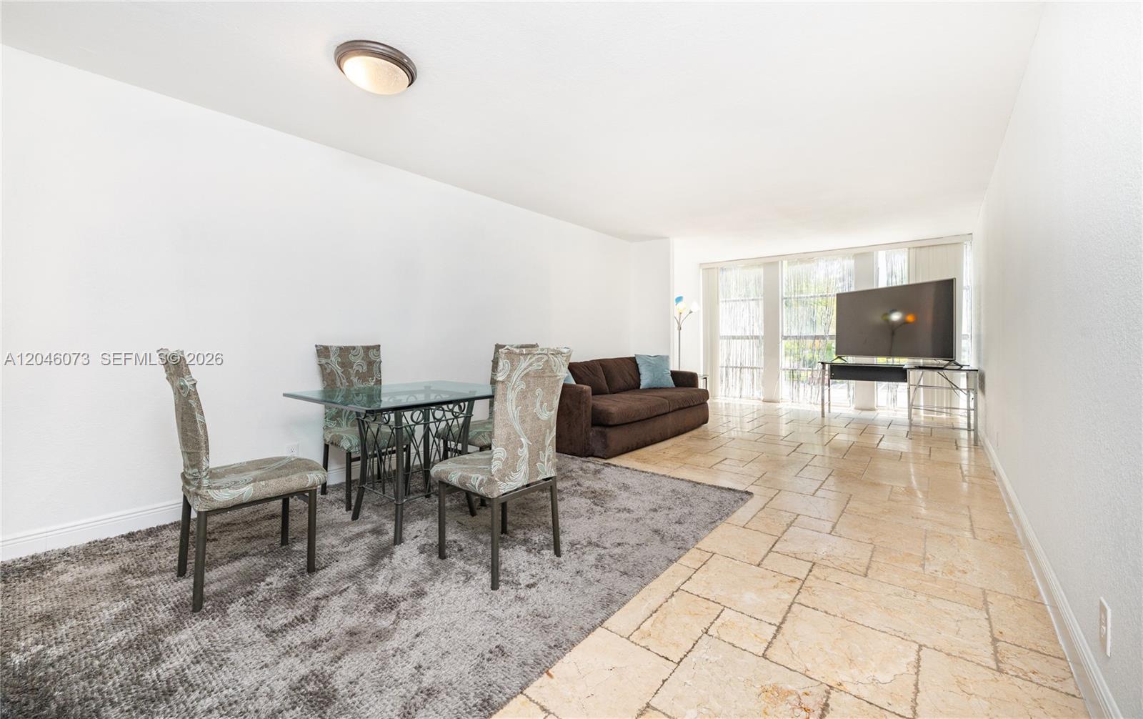 A living and dining area features tile flooring, a glass table, and a brown sofa — 701 Three Islands Blvd # 206, Hallandale Beach FL 33009, HALLANDALE BEACH, FL