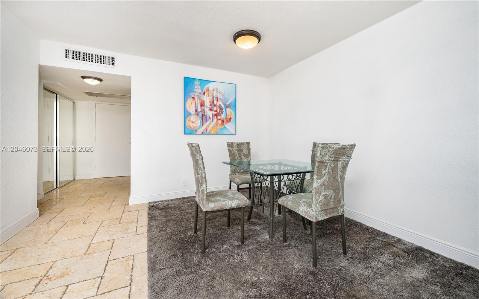 A dining area features a glass-topped table, four patterned chairs, and a dark area rug — 701 Three Islands Blvd # 206, Hallandale Beach FL 33009, HALLANDALE BEACH, FL