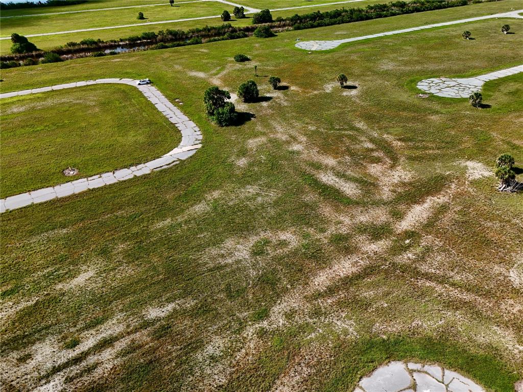 An aerial view shows a vacant, grassy lot with paved driveway stubs and scattered vegetation — 12384 BONITA PLACE, PLACIDA, FL