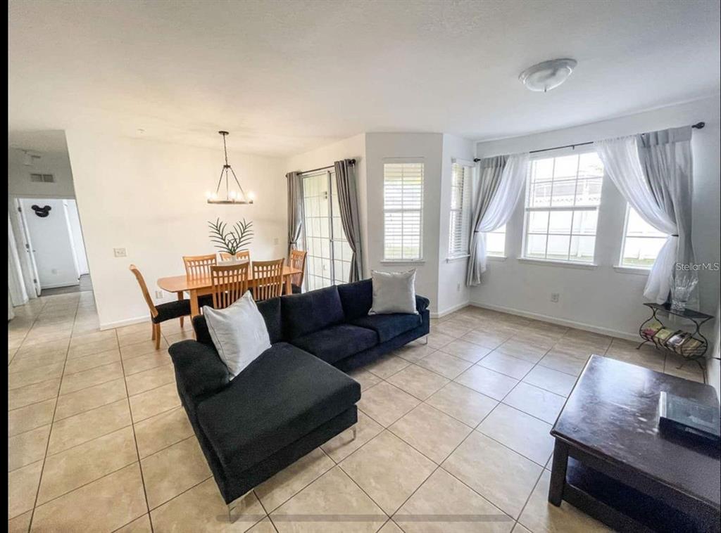 A living room and dining area with tile floors, a dark sectional, and large windows — 202 TERRACE RIDGE CIRCLE UNIT 202, DAVENPORT, FL