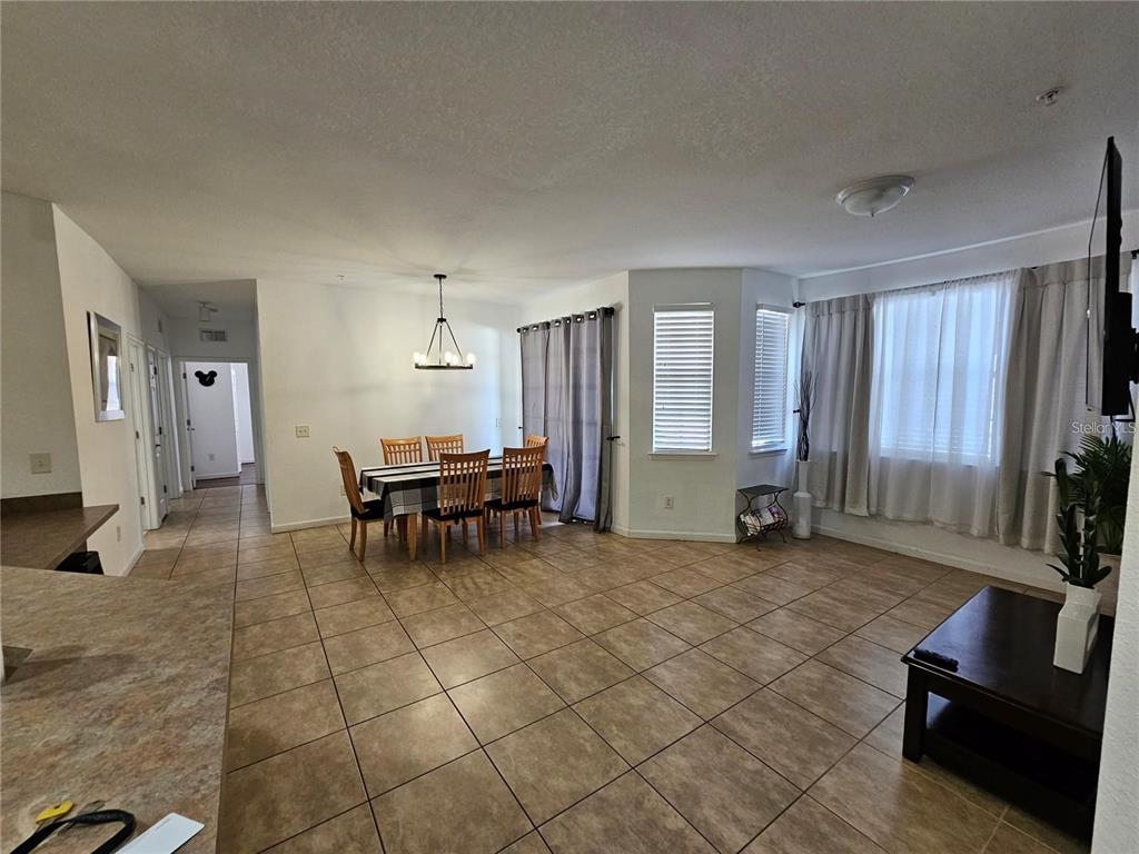 An open-concept dining and living area features tile flooring, neutral walls, and large windows — 202 TERRACE RIDGE CIRCLE UNIT 202, DAVENPORT, FL